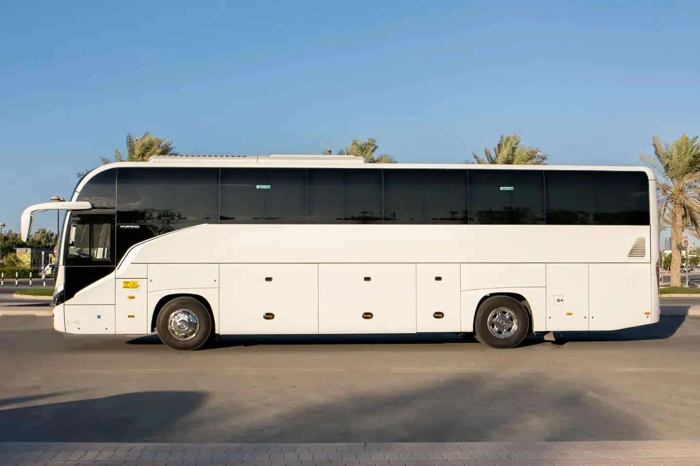 Side view of an illustrative white group coach for a 50-seater bus with driver request in Dubai