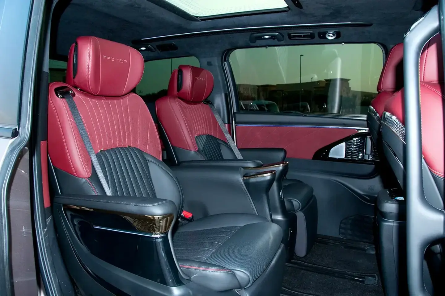 Red and black second-row seating photographed in a GAC M8 executive MPV used to illustrate a Dubai chauffeur request